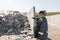 Landfill worker directing skid steer loader on the waste heap