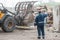 Landfill worker directing skid steer loader on the waste heap, rear view