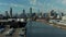Landing footage of Newtown Creek waterfront. Cars on fenced parking lot and industrial site behind. Skyline with