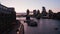 Landing footage on waterfront promenade. People enjoying evening. Tower Bridge and downtown skyscrapers against twilight