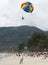 Landing on a parachute in the blue sky tropical beach. Two Chinese tourists flying on a parachute over the sea on a beach in