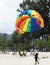 Landing on a parachute in the blue sky tropical beach. Two Chinese tourists flying on a parachute over the sea on a beach in