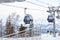 Landing place to a gondola cableway booth suspended on a cable where sits people with skis and snowboards on a background of