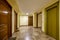 Landing of a residential apartment building with brown marble floors and ocher green metal elevator