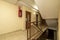 Landing of a residential apartment house with a staircase with light terrazzo floors, red painted metal railings and double