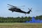 Landing of swedish military helicopter Blackhawk UH-60. Military armed men with smoke bomb near forest under blue sky