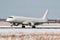 Landing of a white passenger jet plane on the runway of a winter airport