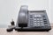 Landline ip phone stands on a wooden table in the office