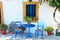 Landmark photo of blue chairs with table in typical Greek town