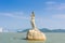 Landmark of Zhuhai city of China. Statue of Fish Woman, fisher girl stature with background of sea, island, and tall buildings