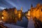 Landmarks of Bruges (Brugge) - traditional buildings near the water canal, boats and wooden jetty.