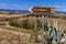 Landscape along via Francigena with Mud road, fields, trees and vineyard. Sign showing the route the via francigena