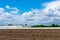 Landscape with asparagus field and greenhouse at blue cloud sky.