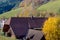 Landscape of autumn countryside wooden farmhouses on green hill and mountains in the background,Germany