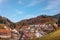 Landscape autumn countryside with wooden farmhouses on green hill and rugged mountains in the background ~ Idyllic view of vill