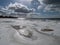 Landscape of Baltic sea and beach with ice and snow formations on the shore in bright sunlight. Frozen ice blocks and sea water in