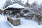 Landscape  with barbeque area and winter garden.  Snowbanks of white snow,cottages, pine trees background.