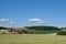 Landscape in Bavaria with green fields and meadows against a blue sky. A few sheep are grazing on a gentle hill far away