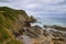 Landscape of a beach with grass, rocks and a clody sky