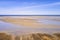 A landscape of the beach shore and blue sky background with copy space on a summer day. The sea or ocean during low tide