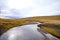 Landscape of Blondus, blue/white sky, grass, water and a flowing river in the middle i