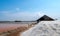 Landscape of brine salt farm with blue sky on sunny day. Salt warehouse. Pile of organic sea salt. Raw material of salt industrial