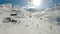 Landscape from a chairlift of a ski resort. Skiers skiing in snowy mountains on sunny winter day