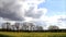 Landscape clouds trees and field in April