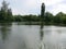 Landscape with cloudy sky, Cumulus clouds, green forest and lake with reflections in the water with willows and reeds