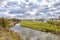 Landscape with cloudy sky, river, field and church