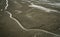 Landscape of coastal mud. Loneliness. Beach on tide. Water canal with natural pattern. Grey clay. Coastal ecosystems.