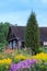 Landscape in countryside with old wooden rural house building and bright wildflowers in bright warm summer day.