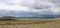 Landscape of a deserted area surrounded by hills under a cloudy sky on a gloomy day