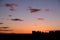 Landscape, with disturbing red sunset in the sky and few clouds above dark skyline and some buildings silhouettes at far