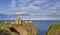 Landscape of Dunnottar Castle ruins withh dark clouds and ocean