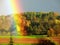 Landscape with fields and autumn forest and great rainbow