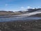 Landscape of Fimmvorduhals hiking trail. Eyjafjallajokull glacier and volcano, lava ash, blue stream from melting snow