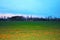 landscape, freshly cultivated field with background the farm and a beautiful blue sky.