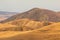 Landscape of the Georgian steppe Udabno in Georgia. Yellow-gold grass, wilde land and blue sky. Endless fields. Mountain in the