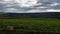 Landscape of green fields, towering mountains, and  rolling hills backdrop during gloomy weather