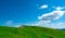 Landscape of green grass and rock hill in spring with beautiful blue sky and white clouds. Countryside or rural view. Nature