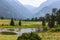 Landscape of Green Meadow with Pond Against Rocky Mountains Covered in Haze Because of Wildfires