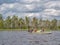 Landscape of harsh Karelian nature with three women in boat. Active extreme ecotourism in Karelia. Water rafting