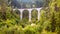 Landscape with high bridge and small house, Filisur, Switzerland. Panorama of Alpine forest. Scenic view of viaduct in summer