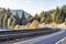 Landscape with a highway and a railway winding along the Columbia River with mountain ranges on the banks overgrown with autumn