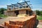 Landscape of house under construction with pile of brick in foreground.