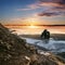 Landscape Hvitserkur in Iceland, young traveling hiking down from cliff to black sand beach in sunset