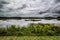 Landscape image at Bombay Hook NWR in Delaware with goldenrod in the foreground and a stormy sky in the background.