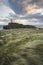 Landscape image of Twr Mawr lighthouse with windy grassy footpath in foreground at sunset