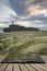 Landscape image of Twr Mawr lighthouse with windy grassy footpath in foreground at sunset concept coming out of pages in book